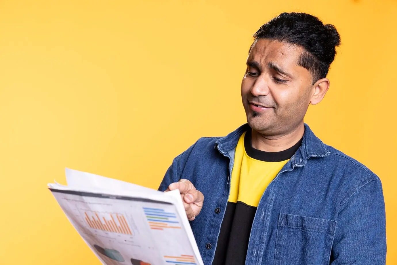 Jeune homme indien feuilletant des documents papier d’un rapport d’audit financier.